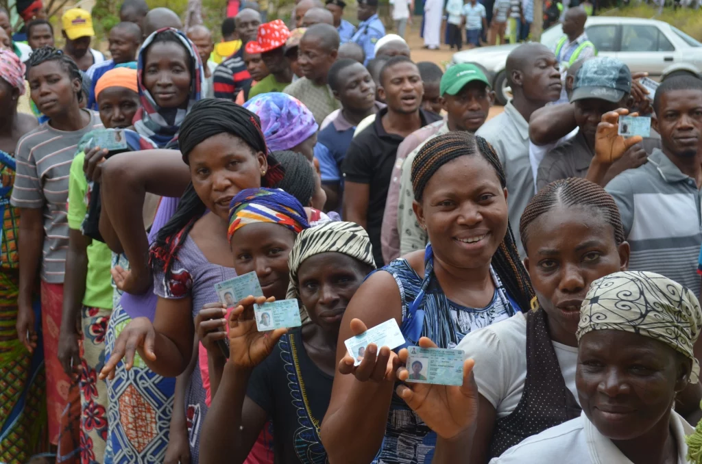 Picture showing women holding their permanent voters card waiting to vote in an election.